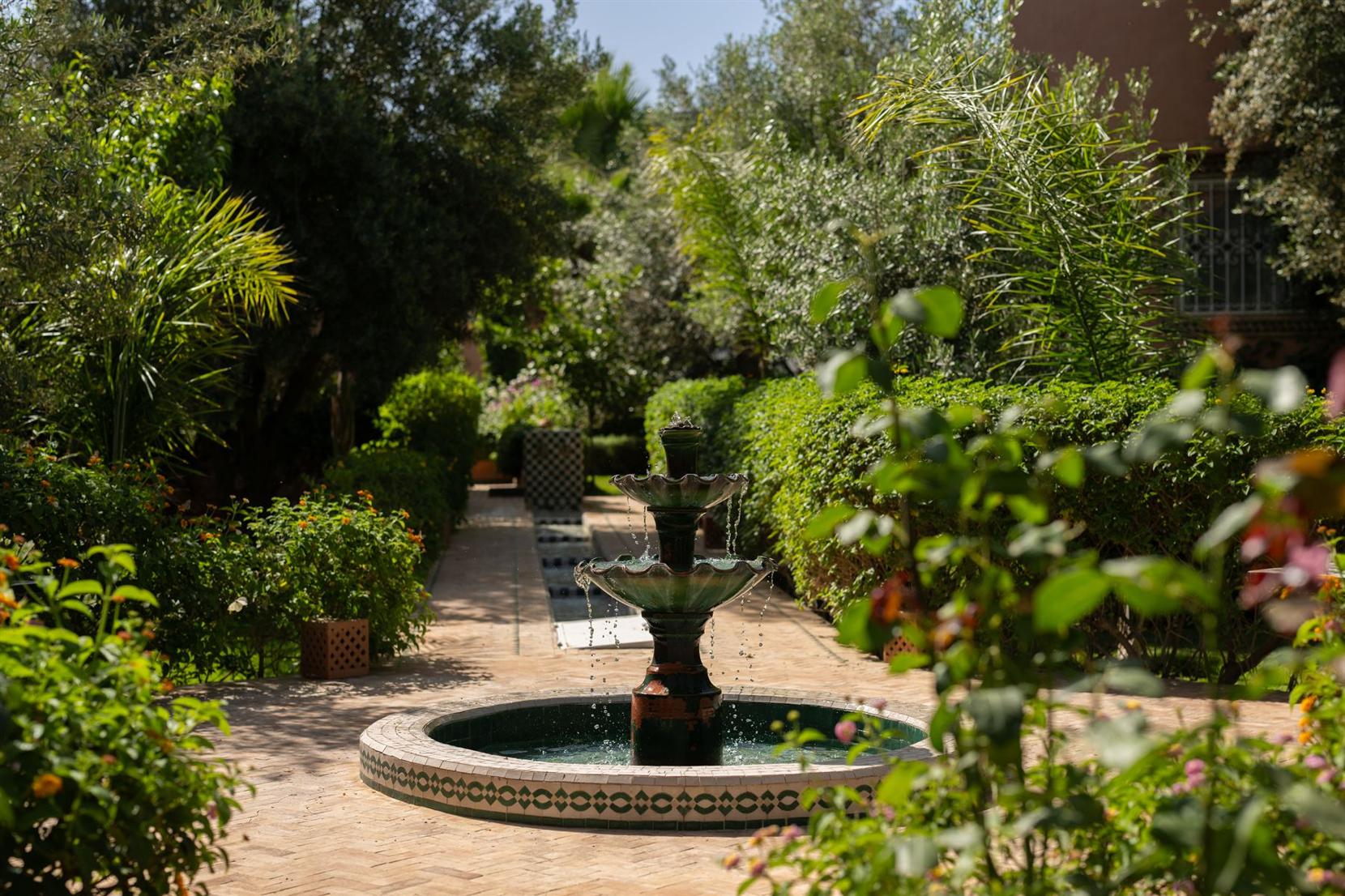 Le jardin d'un établissement, avec une fontaine en zellige.